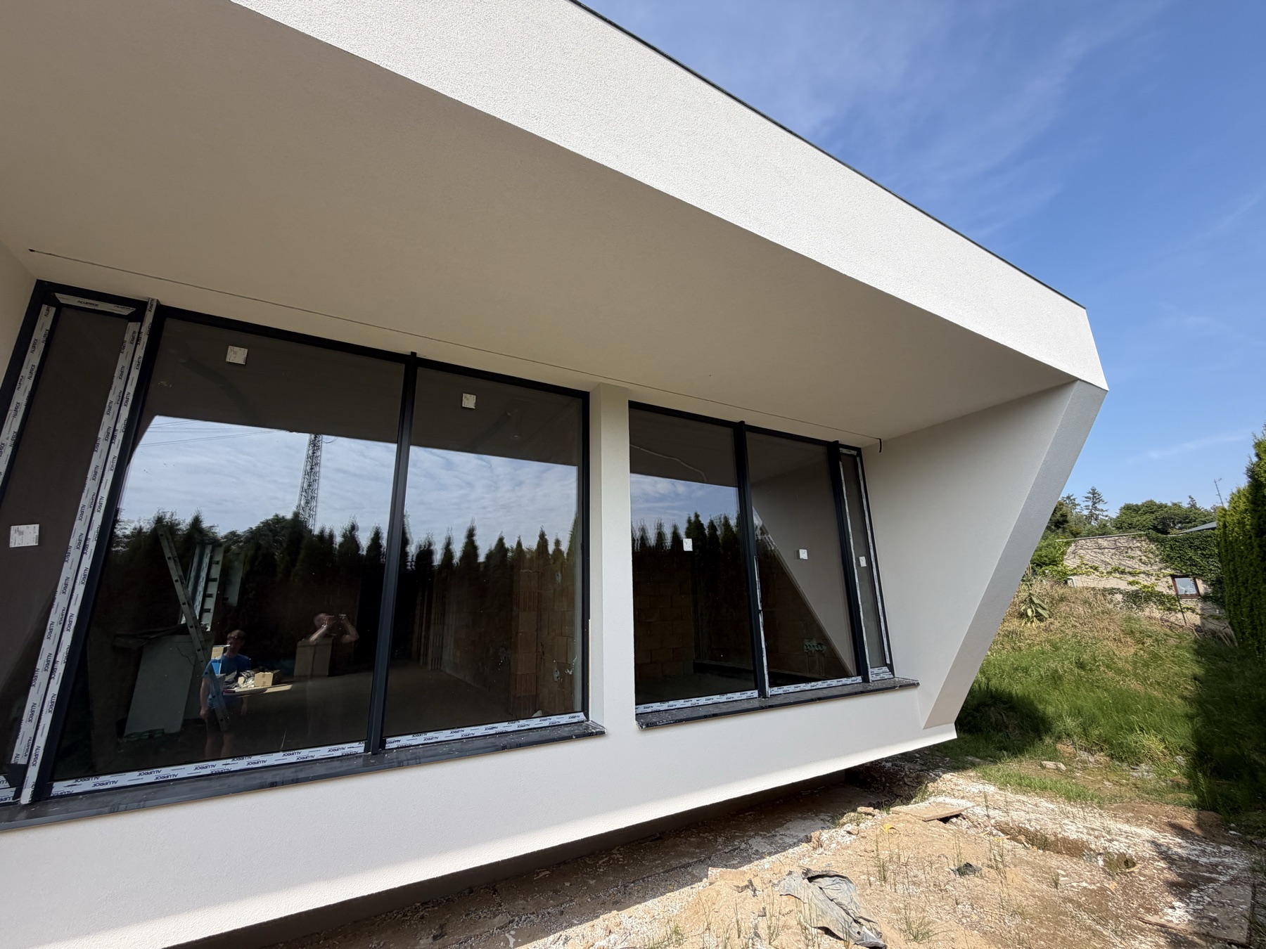 Hotová fasáda novostavby — panoramatické zasklení a předsazená střešní deska