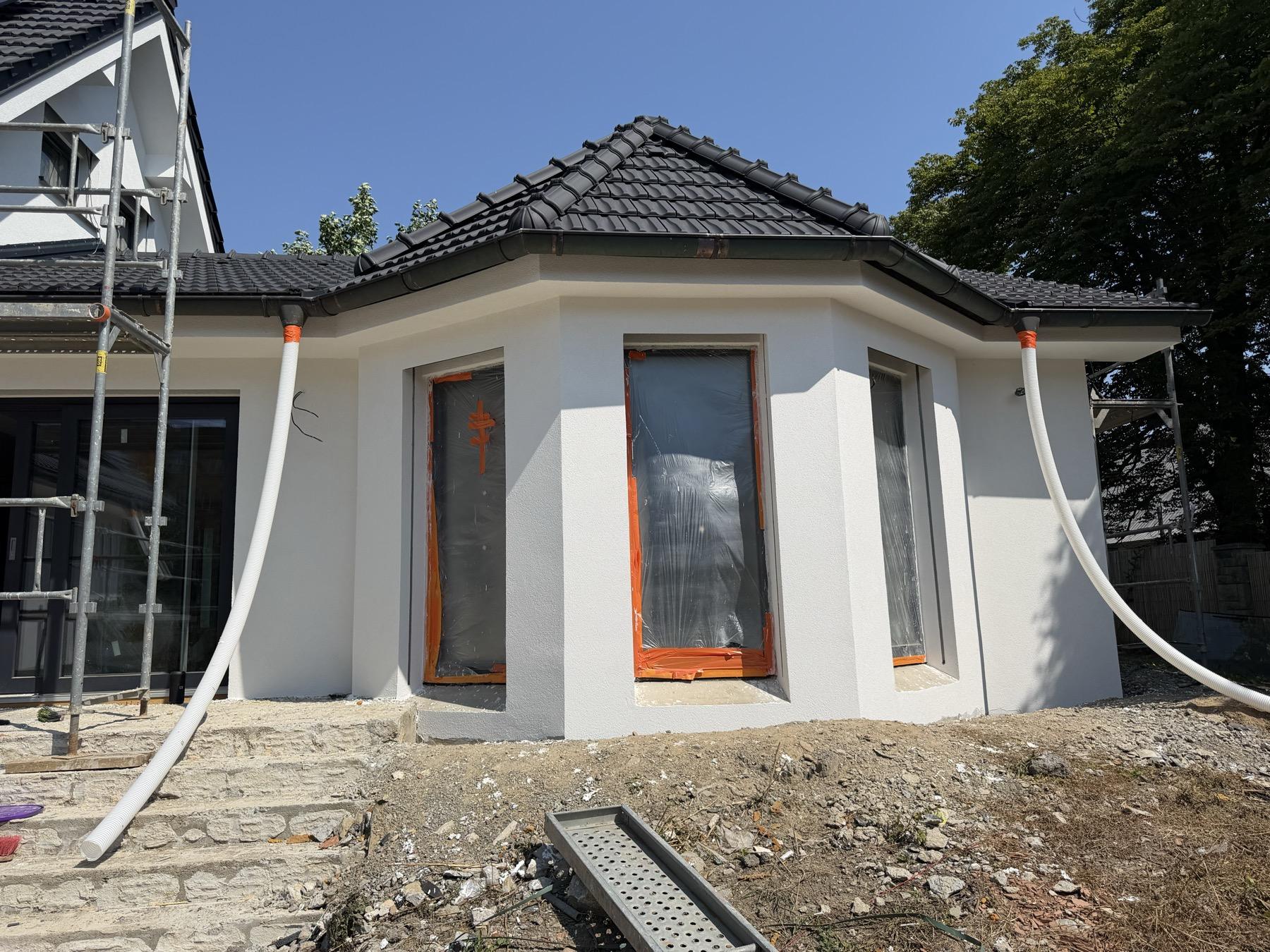 Dokončená fasáda rodinného domu s detaily kolem oken, lešení u štítu