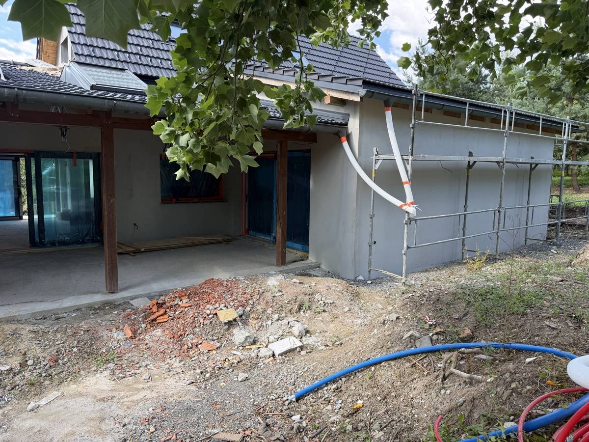 Rodinný dům během prací, vzrostlá zeleň přímo u stěny